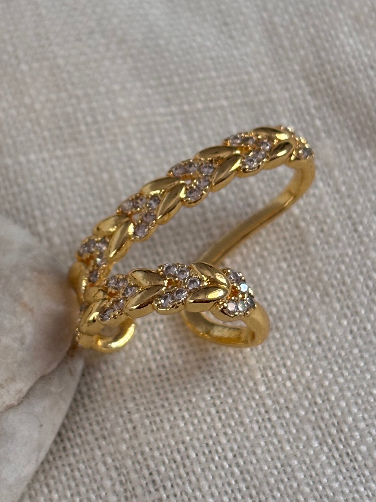 Gold ring with diamond accents on a light gray fabric background