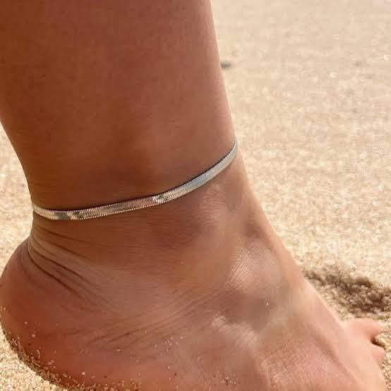 Silver anklet on a foot with sand in the background