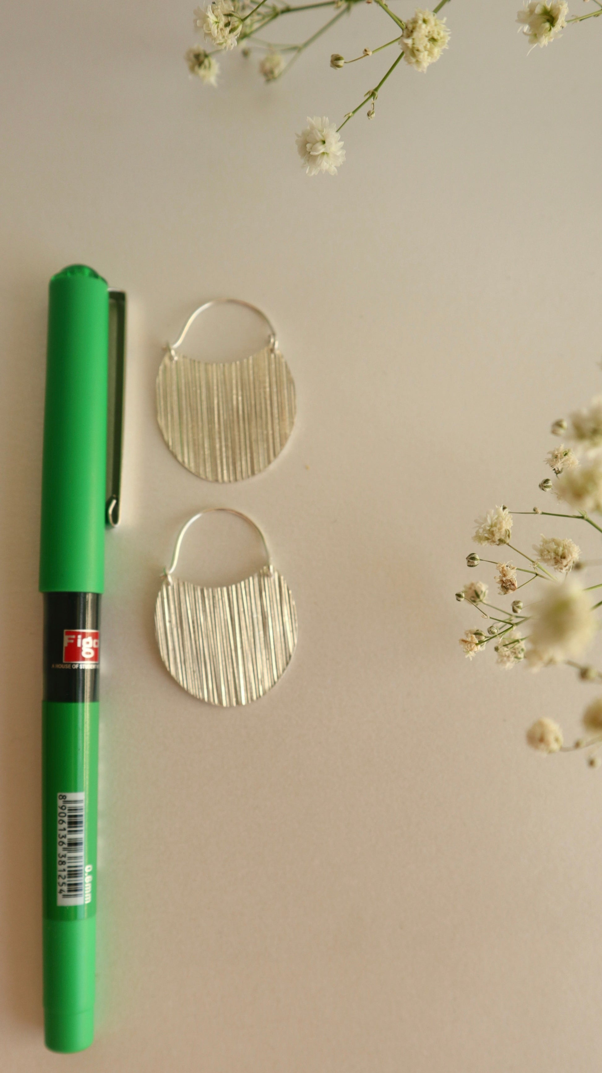 Small hoop earrings and green pen for size reference