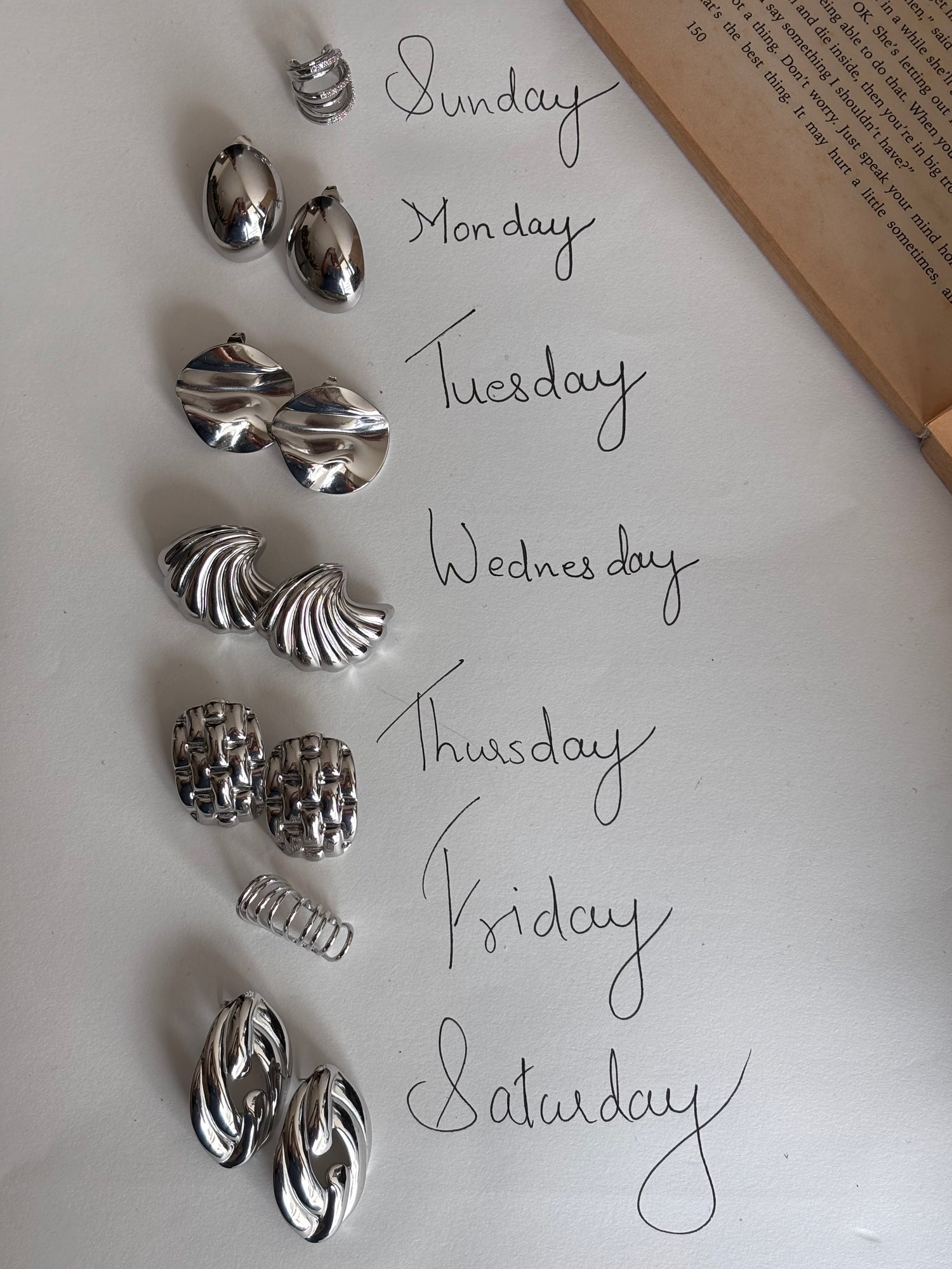 A layout of stainless steel silver earrings that can be worn for every day of the week