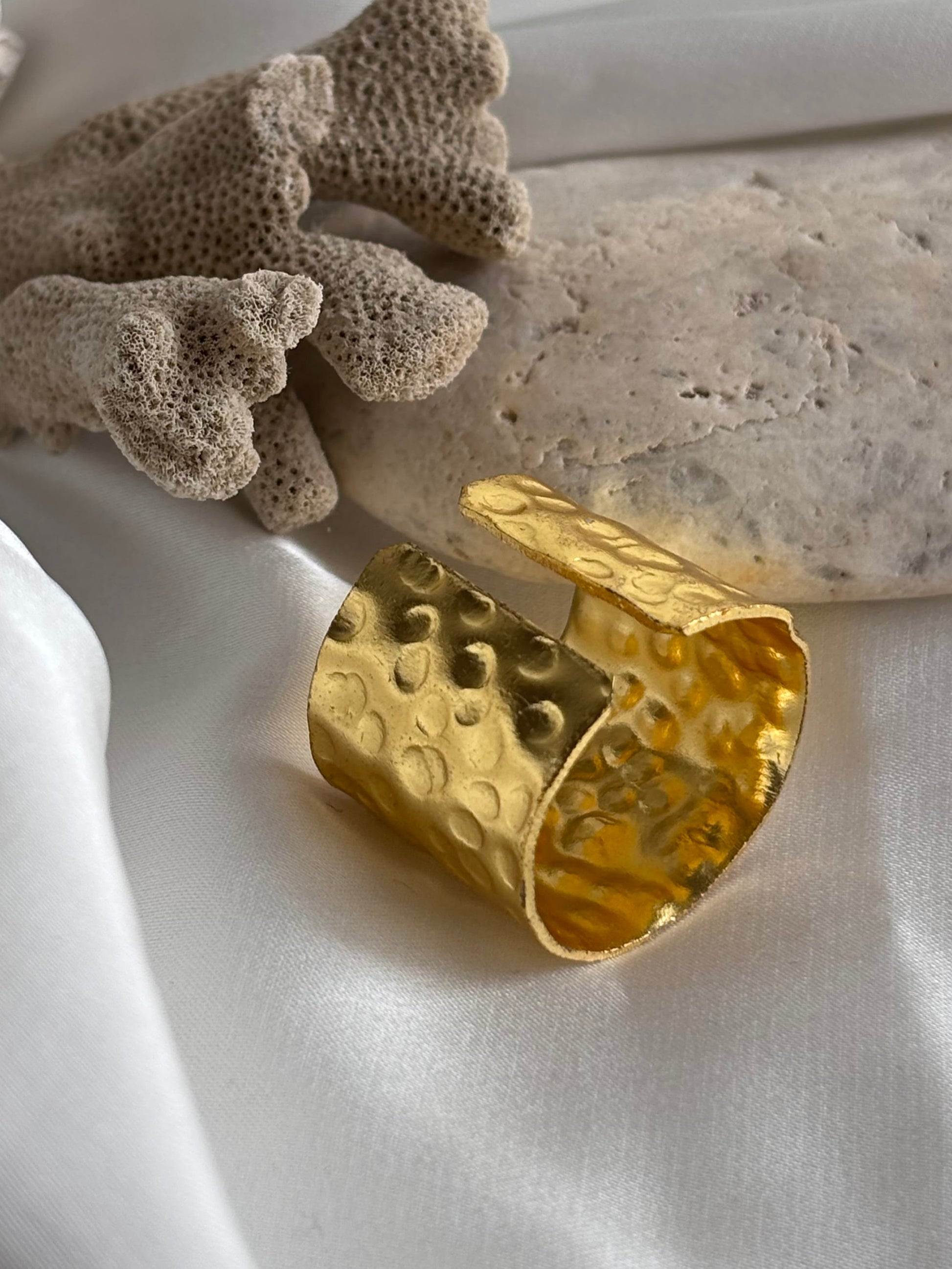Gold ring with textured design on a white fabric background
