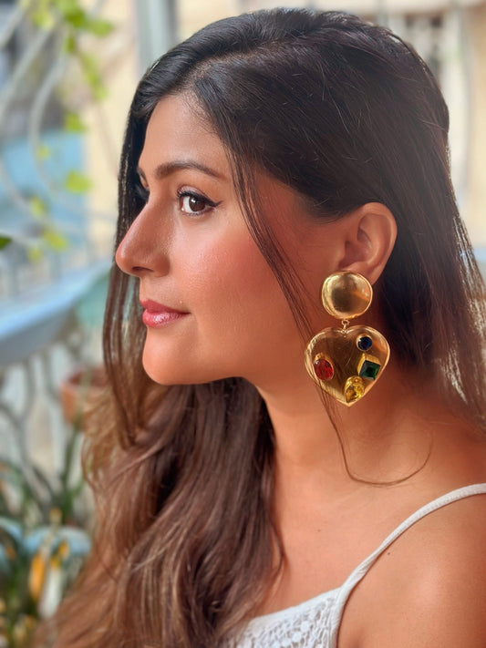 Woman wearing gold heart-shaped earrings with a blurred background