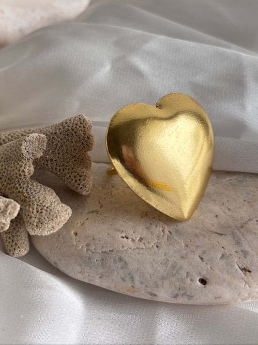 Gold earring on a textured beige surface