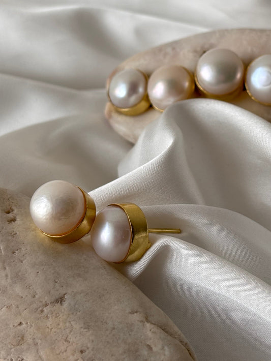 Pearl stud earrings on a white fabric background