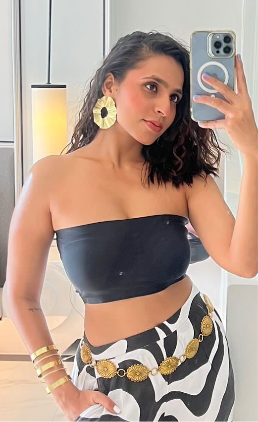 A person wearing large gold-plated earrings with a pattern that resembles wild flowers.